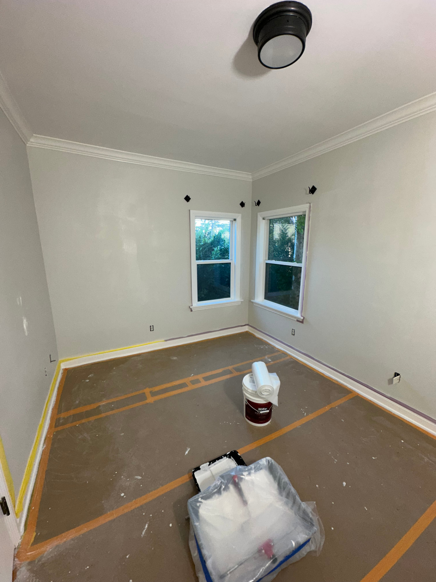 Bedroom in Glendale during an interior remodel with patched and primed walls, new crown molding, and floors masked for painting