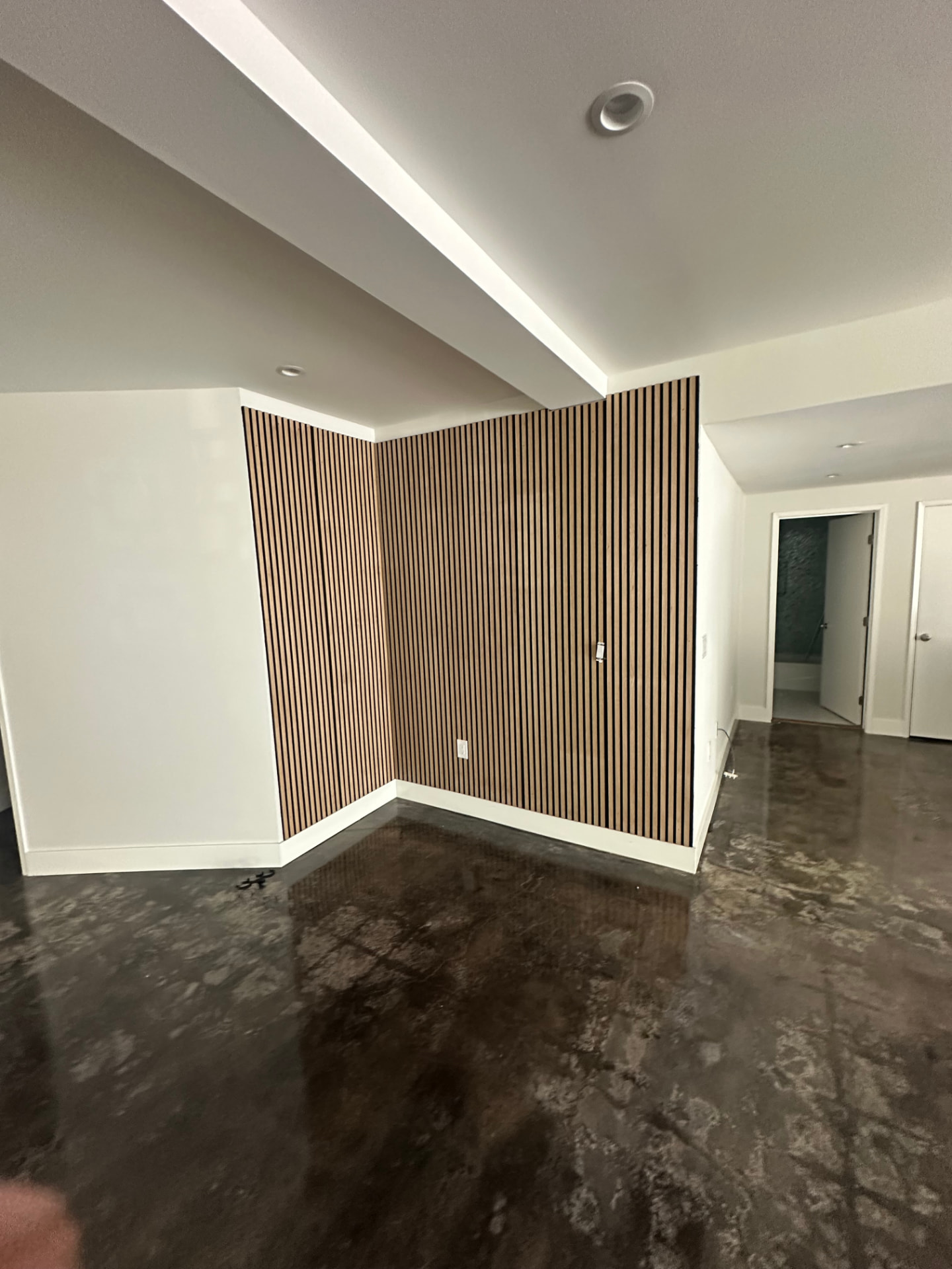 Interior remodel in Sherman Oaks with a white oak slat feature wall, cove lighting along the ceiling, and polished concrete flooring