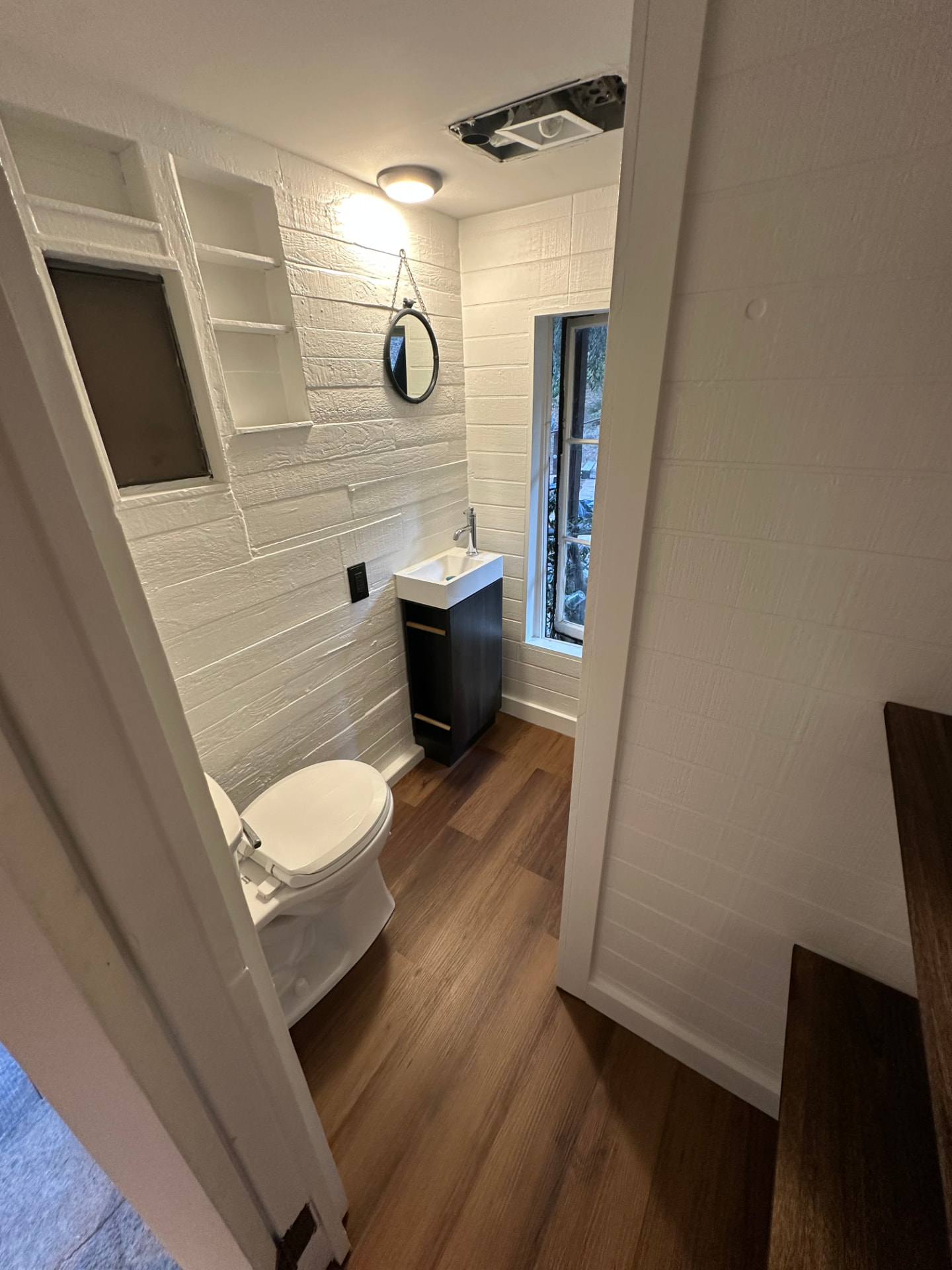 Half bathroom remodel in Hollywood with painted white shiplap walls, built-in niche shelving, and dark wood vanity