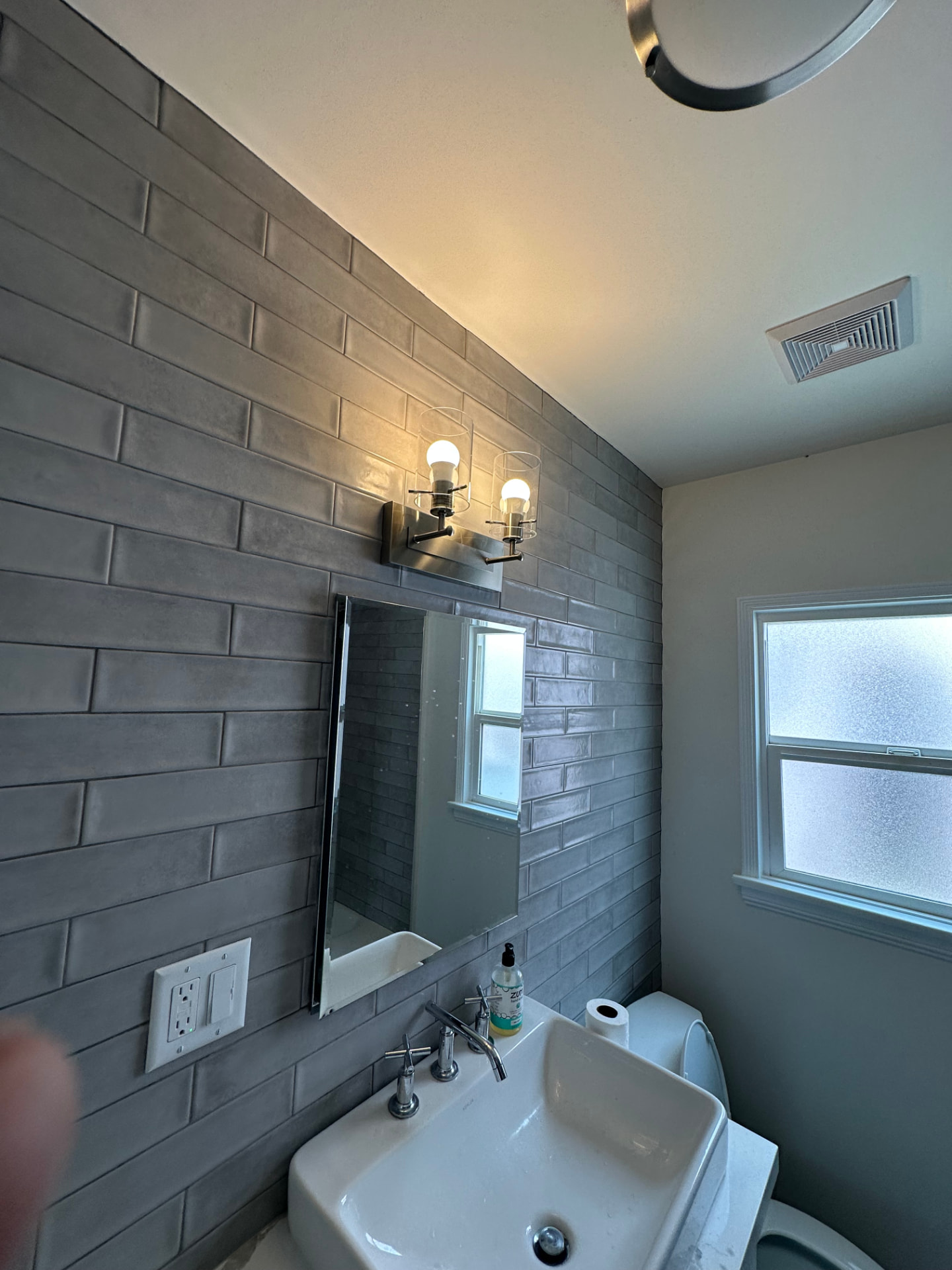 Powder room remodel in West Los Angeles with floor to ceiling gray handmade tile, wall mount sink, and polished nickel lighting
