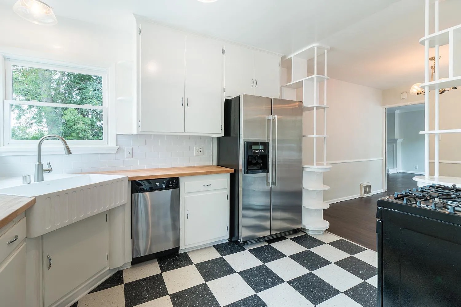 Renovated kitchen in West Hollywood with white shaker cabinets, butcher block counters, and a fluted apron-front sink