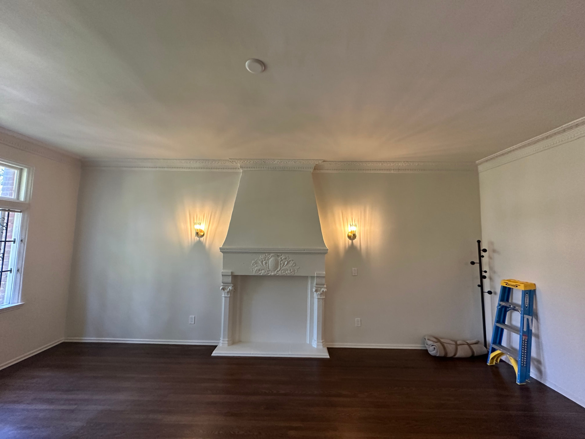 Restored ornate white fireplace mantel and crown molding in a formal Los Angeles living room after interior remodeling